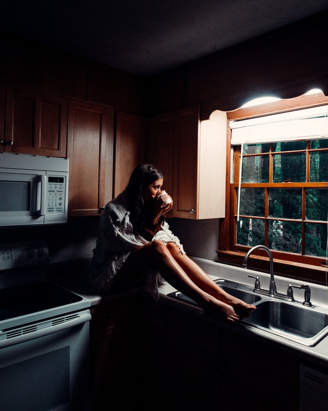 Woman drinking coffee in the kitchen alone